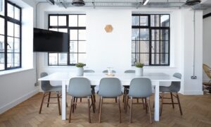 White table with green chairs surrounding it in white room with black framed windows