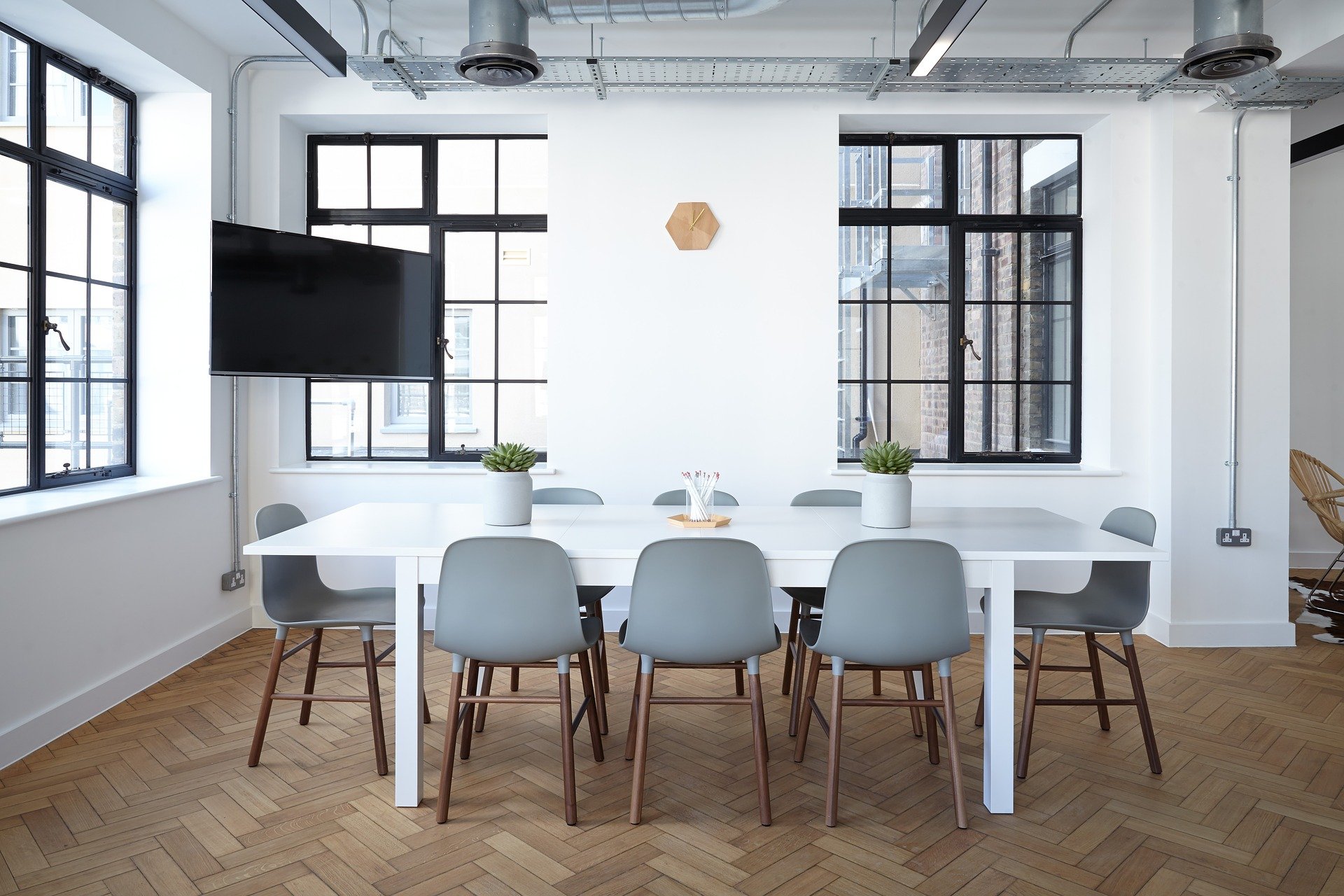 White table with green chairs surrounding it in white room with black framed windows